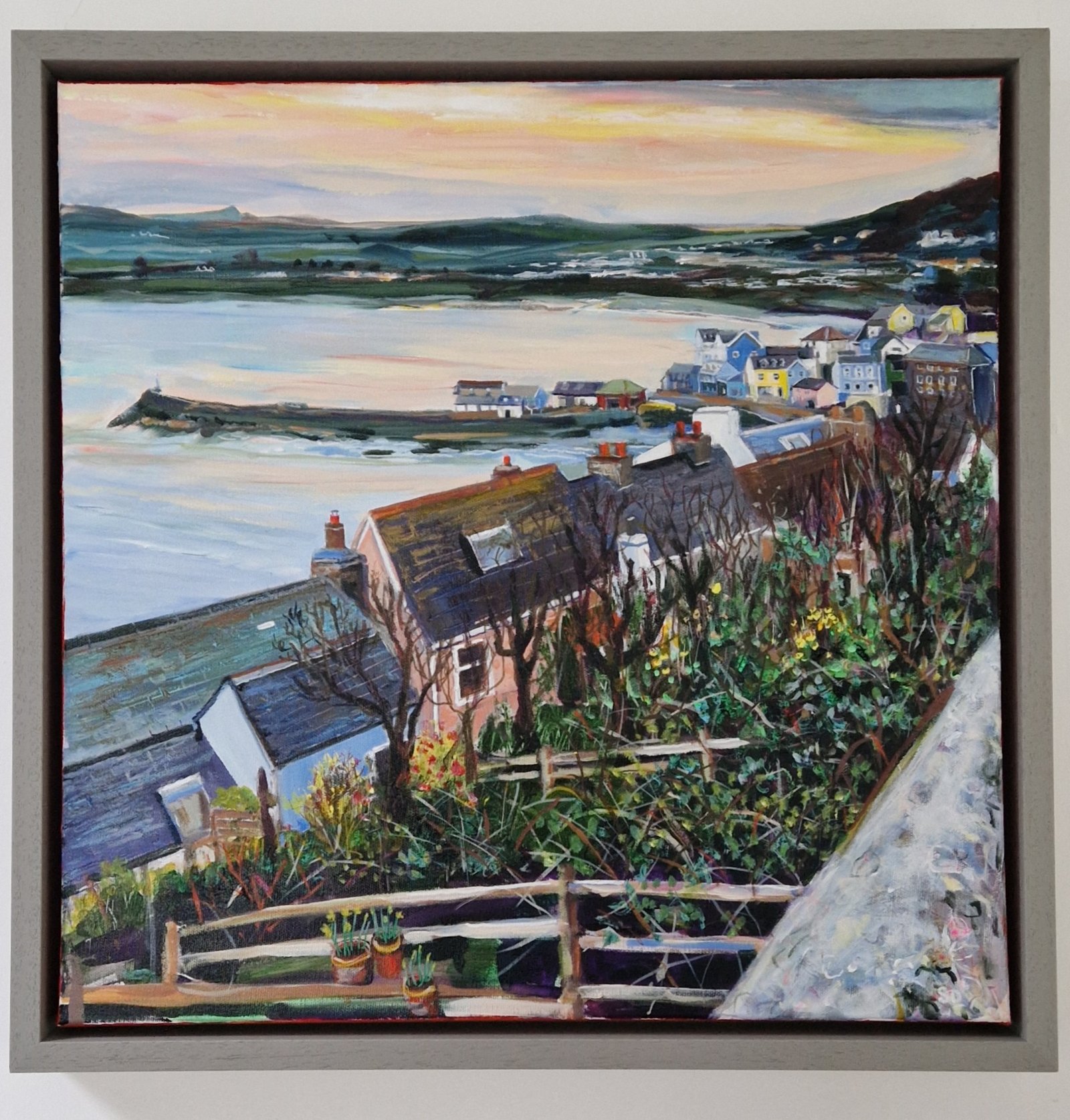 Atmospheric evening painting of New Quay harbour in Wales viewed from above with rooftops, gardens and calm coastal light by Sue Dewhurst.