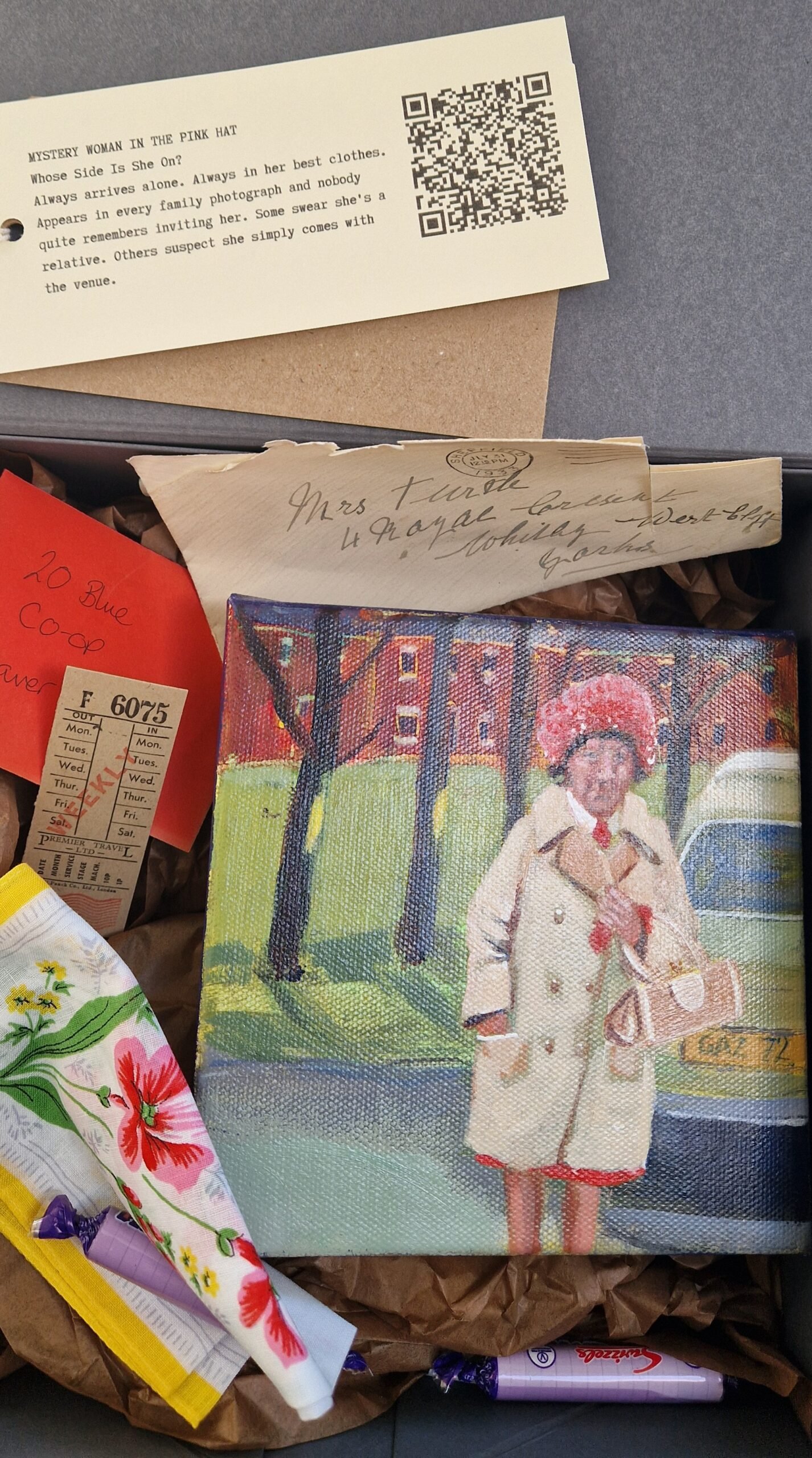 Close-up of the "Mystery Woman in the Pink Hat" relic box installation by British artist Sue Dewhurst. Arranged are a handwritten letter, an old-fashioned shopping list, a handkerchief and a packet of Parma Violets sweets, suggesting the traces and memories of an elegant but enigmatic woman from the 1970s. Part of the immersive "From the Outside Looking In" exhibition exploring memory, ordinary lives and nostalgia.